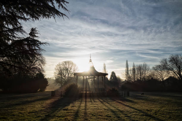 A park bandstand, early on a frosty, slightly misty, winter morning with the sun rising behind the old bandstand in Beckenham Recreation Ground in Beckenham, Kent (South East London). Thought to be the only one of its kind still in existence, the bandstand is Grade II listed but was falling into disrepair at the time this photograph was taken: it has since been restored to its Edwardian splendour. The bandstand was where David Bowie (who lived in Beckenham at the time and who started his career in the town) performed at a free festival which he compèred and helped to organise in 1969. It is locally known as the “Bowie Bandstand”.