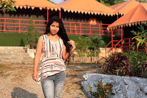 Young woman of Indian ethnicity standing portrait outdoors during summer season in tourist resort, Shivpuri, Rishikesh, Uttarakhand India.