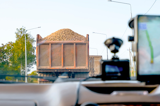 A car loaded with rubble is moving along the highway. View from the windshield of the car. The rubble is not covered with a protective tarpaulin