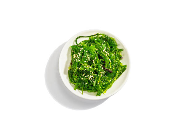 ensalada de algas chuka con semillas de sésamo aisladas sobre fondo blanco. luz dura de moda, sombra oscura - wakame salad fotografías e imágenes de stock