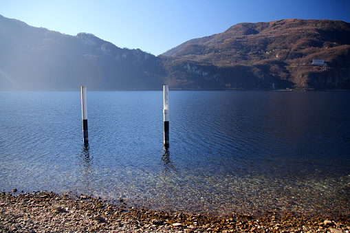 The traditional black and white poles of a boat mooring on Como Lake in Italy