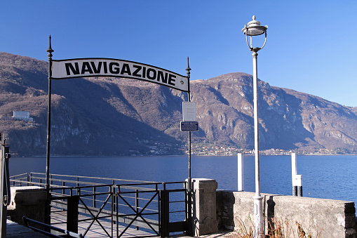 El letrero de Navigazione en la zona de embarque del ferry que atraca de Abbadia Lariana en el lago de Como photo