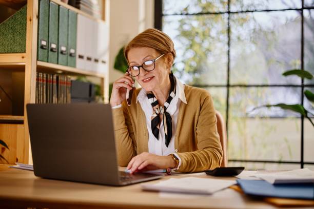 istock Happy businesswoman using mobile and laptop while working at home 1367180249