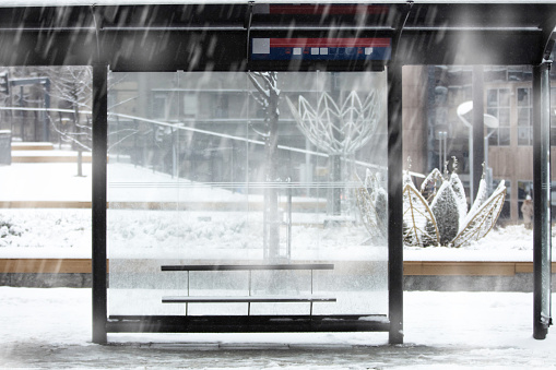 Empty urban bus stop during heavy winter snowfall.