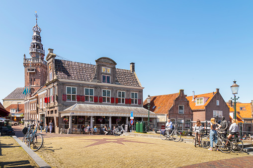 Monnickendam, The Netherlands on May 28, 2021; People on the terrace of a cafe in the former weigh house in the small picturesque fishing village of Monnickendam in the Netherlands.
