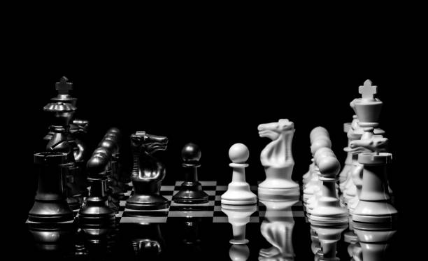 istock Close up of Chess pieces on a reflective mirror board surface with black background 1367183768