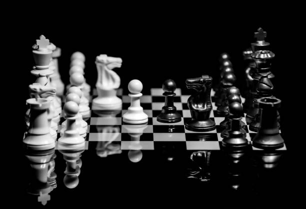 istock Close up of Chess pieces on a reflective mirror board surface with black background 1367183946