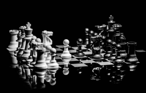 istock Close up of Chess pieces on a reflective mirror board surface with black background 1367184463