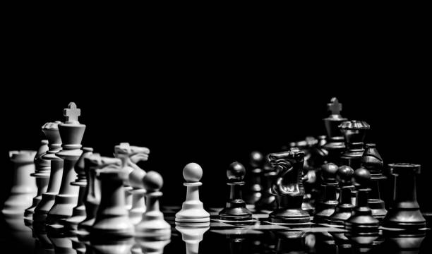 Close up of Chess pieces on a reflective mirror board surface with black background