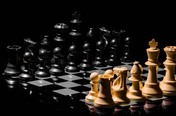 istock Close up of Chess pieces on a reflective mirror board surface with black background 1367184811