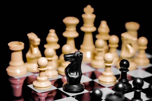 istock Close up of Chess pieces on a reflective mirror board surface with black background 1367185881