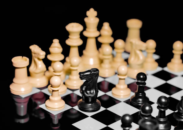 istock Close up of Chess pieces on a reflective mirror board surface with black background 1367186001