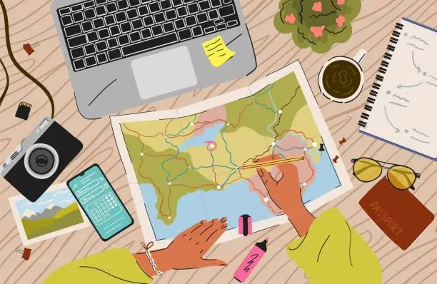 Vector illustration of Woman plan a trip. Travel concept top view vector illustration. Table with map, passport, camera and laptop. Female hand draw trip route on a world map. Holiday adventure, vacation, travel checklist