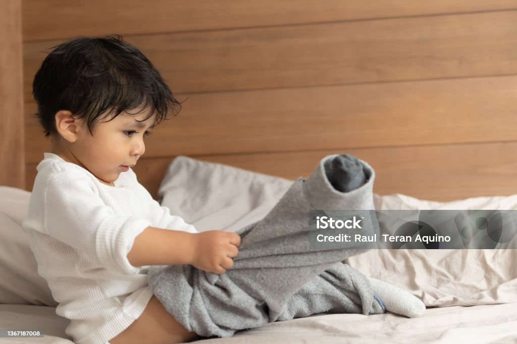 Mexican 2 years old baby putting on socks wrong Getting Dressed Stock Photo