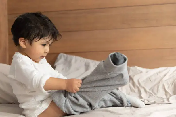 Photo of Mexican 2 years old baby putting on socks wrong