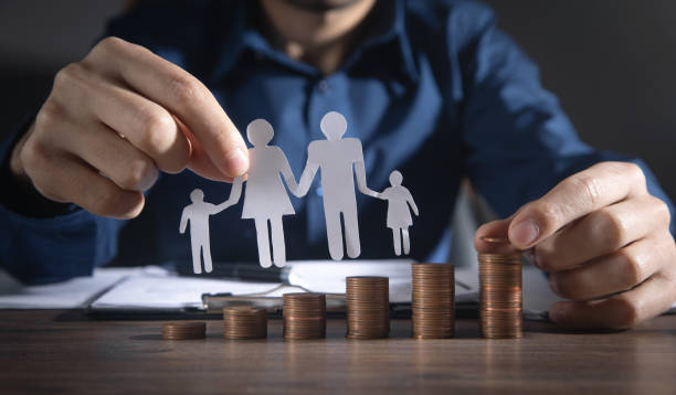 istock Man with a paper family and stack of coins. 1367188074