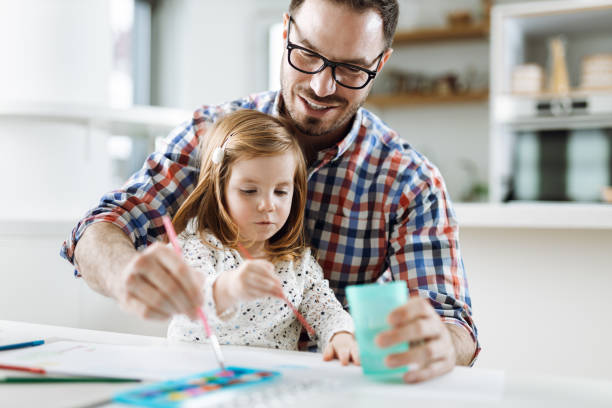istock Happy father assisting his daughter in coloring 1367188081