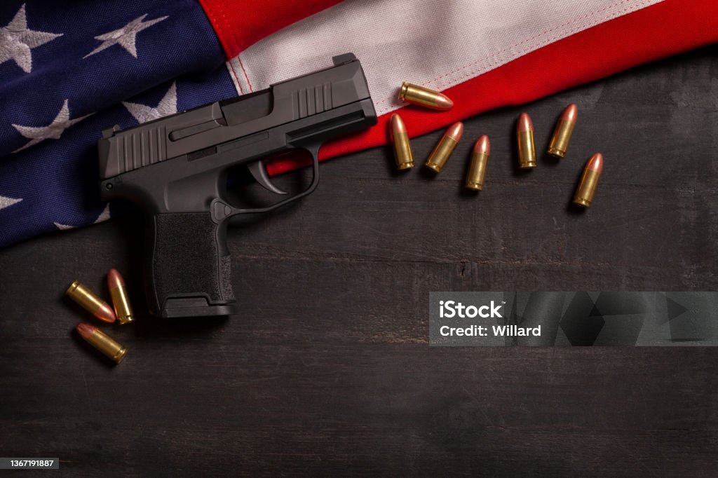 Black pistol and bullets with an American flag on a black wood painted background Gun Stock Photo
