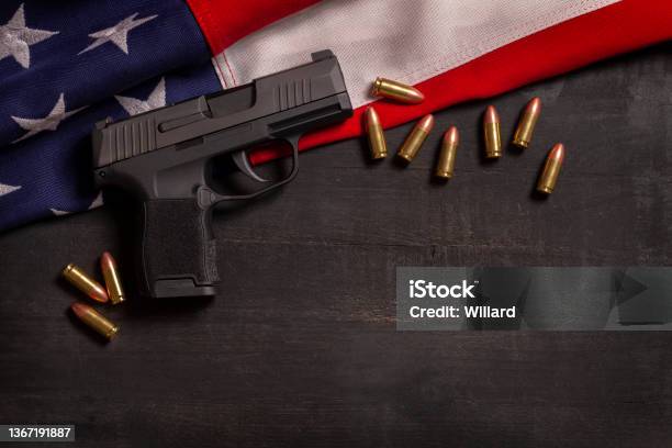 Black Pistol And Bullets With An American Flag On A Black Wood Painted Background Stock Photo - Download Image Now