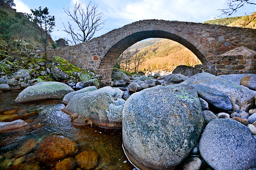 Large pebbles and bridge of Puerto de Candeleda in Garganta de Santa María on a winter day. Sierra de Gredos. Castilla León. Spain.