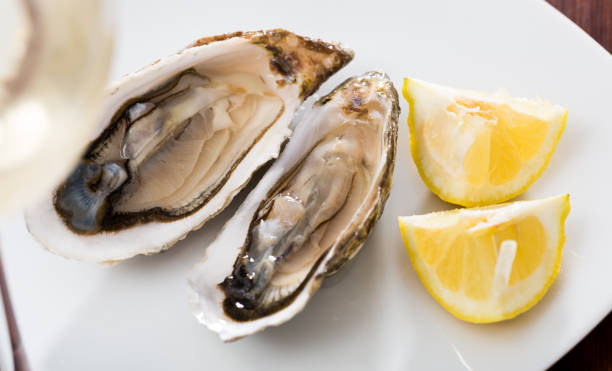 istock Tasty oysters with lemon on plate top view 1367196919