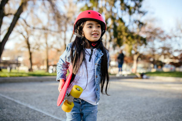 mädchen mit rotem skateboard und helm - skateboard skateboarding outdoors sports equipment stock-fotos und bilder