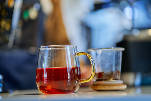 Red tea in a teapot on wooden bar counter. Blurred background