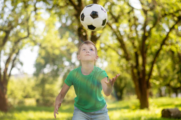 istock Boy looking at flying soccer ball 1367199753