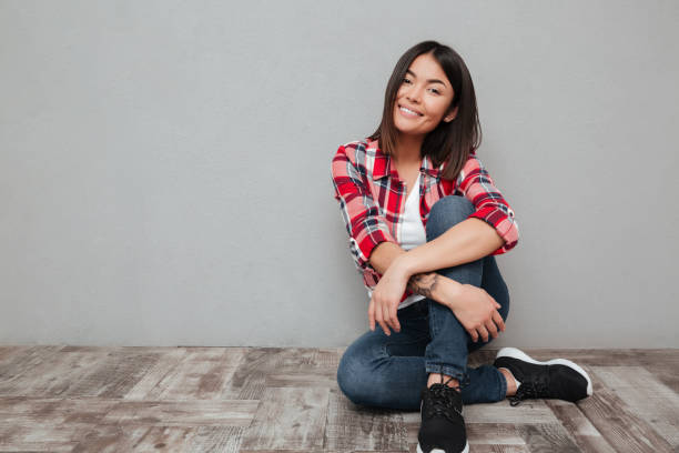 istock Smiling young asian woman isolated over grey wall 1367199781