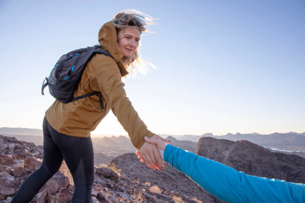 istock Female hiker offers her friend a helping hand 1367200047