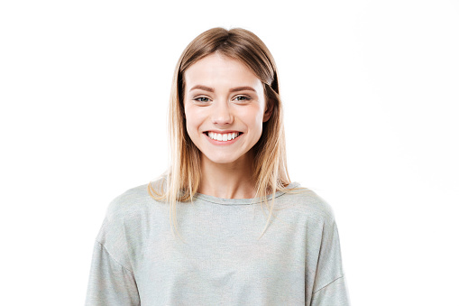 Photo of happy young woman standing isolated over white background. Looking at camera.