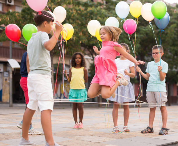 istock Happy tweenagers with balloons playing chinese jump rope in yard 1367200258