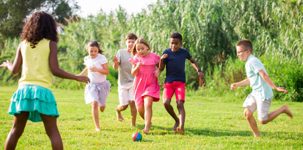 istock Kids running through grass and playing football 1367200369