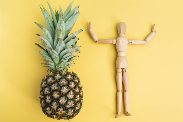 istock Pineapple on a yellow background with a wooden mannequin. Flat lay 1367200515