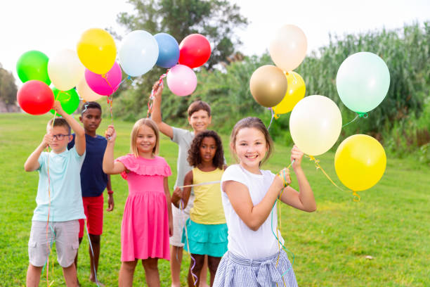 istock Barefoot kids playing with balloons on grass 1367201400