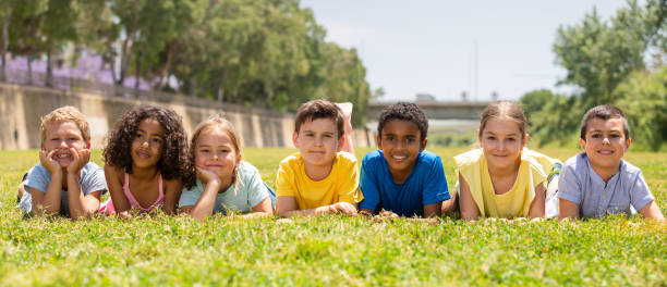 istock Group of school children resting on grass and smiling 1367202572