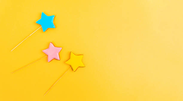 istock Multicolored cookies on sticks on a yellow background Cake decorating tools. Confectionery concept. Top view. Copy Space 1367202717