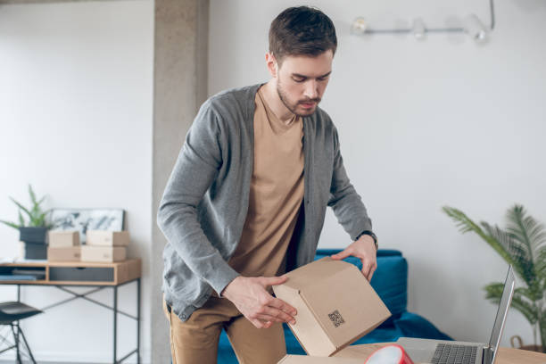 istock Focused calm employee packing wares for shipping 1367203415