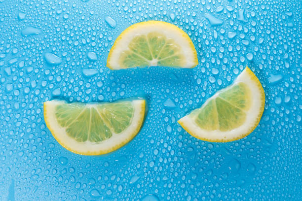 Lemon slices on a blue background with water drops. Background texture
