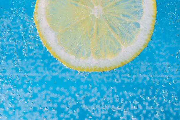 istock Close up of lemon slice under water with bubbles on blue background. Selective focus 1367204806