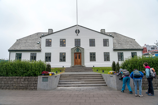 Reykjavik, Iceland - July 19, 2021: Three tourists photographing old Government House of Reykjavik.