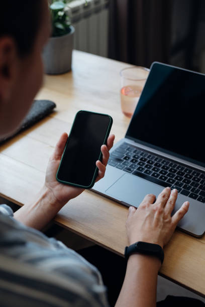 istock Anonymous Young Businesswoman Typing on a Laptop While Holding a Smartphone 1367206883
