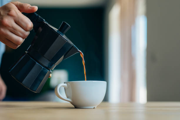 close up photo of an anonymous womanâs hand pouring coffee into a cup - caffeine free imagens e fotografias de stock