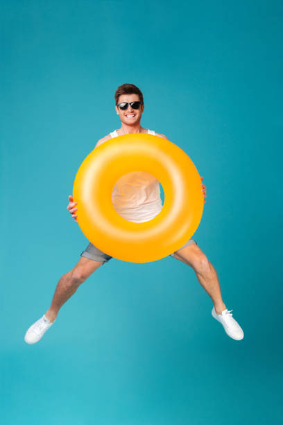 istock Happy excited man in sunglasses holding inflatable ring and jumping 1367208314