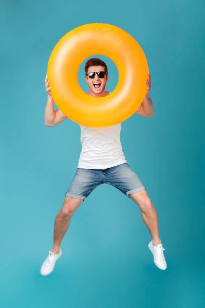 istock Happy excited man in sunglasses holding inflatable ring and jumping 1367208428