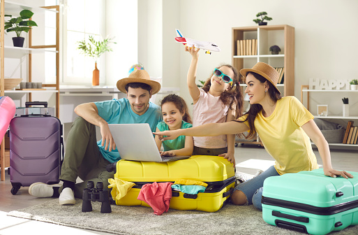 Feliz familia y niños con maleta de viaje comprando billetes reservando hotel online photo