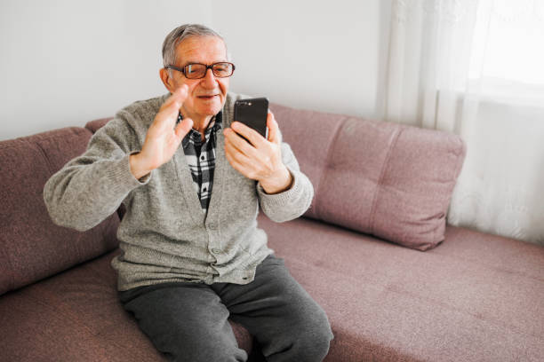 istock Senior man using his mobile phone at home while resting on sofa in living room 1367209253