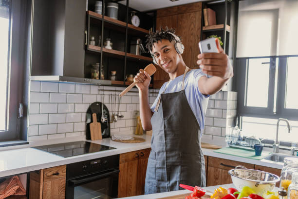 istock Young African American man is having fun in the kitchen and taking selfie 1367210876