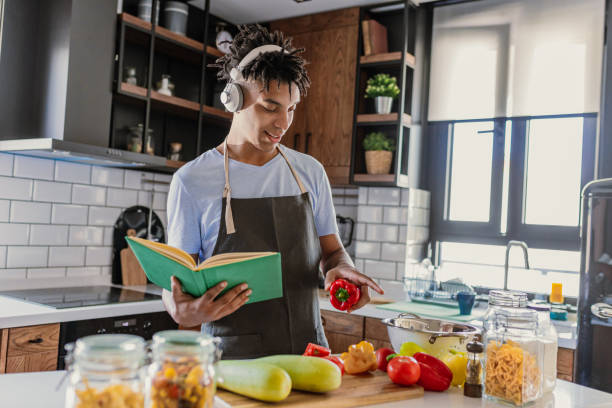 istock African-American young preparing meal in the kitchen and reading recipes 1367210941