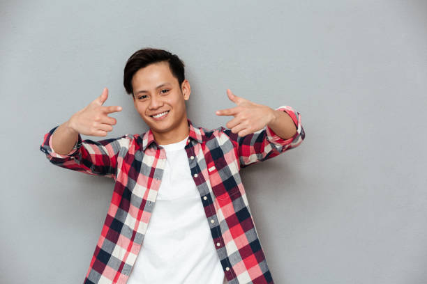 istock Cheerful asian man standing over grey wall. 1367211430